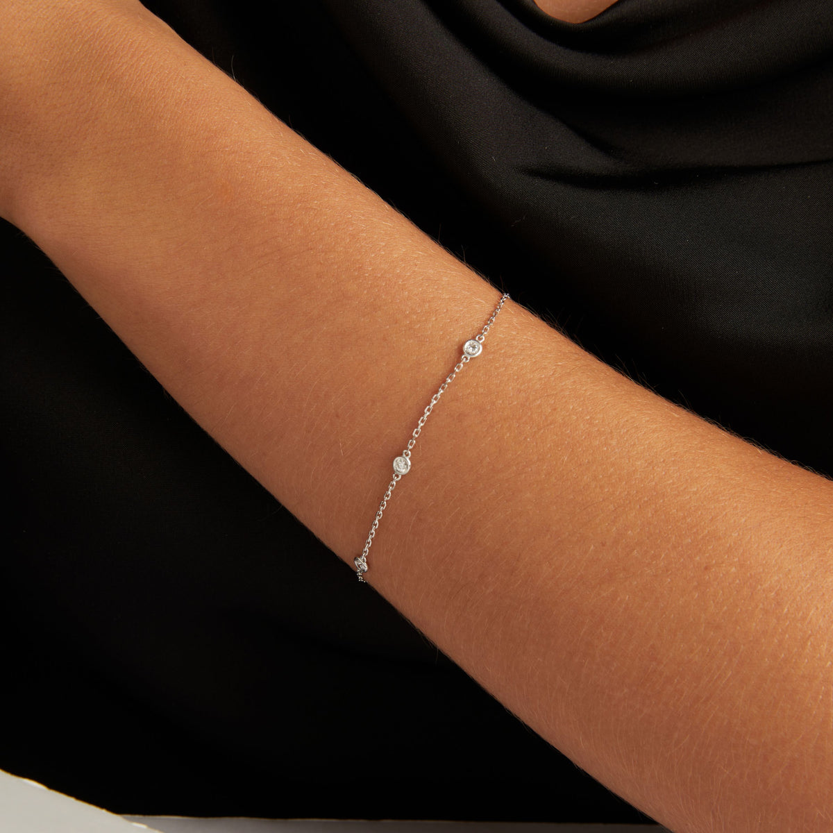 Model. Close up of a woman wearing a black top with a diamond station bracelet.