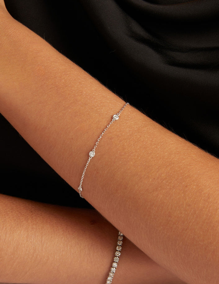 Close up of a woman wearing a black top with a diamond station bracelet.