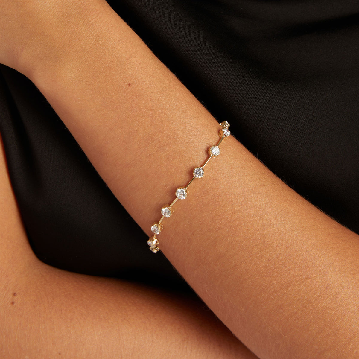 Model. Close up of woman's wrist with a diamond bar bracelet on black shirt. 