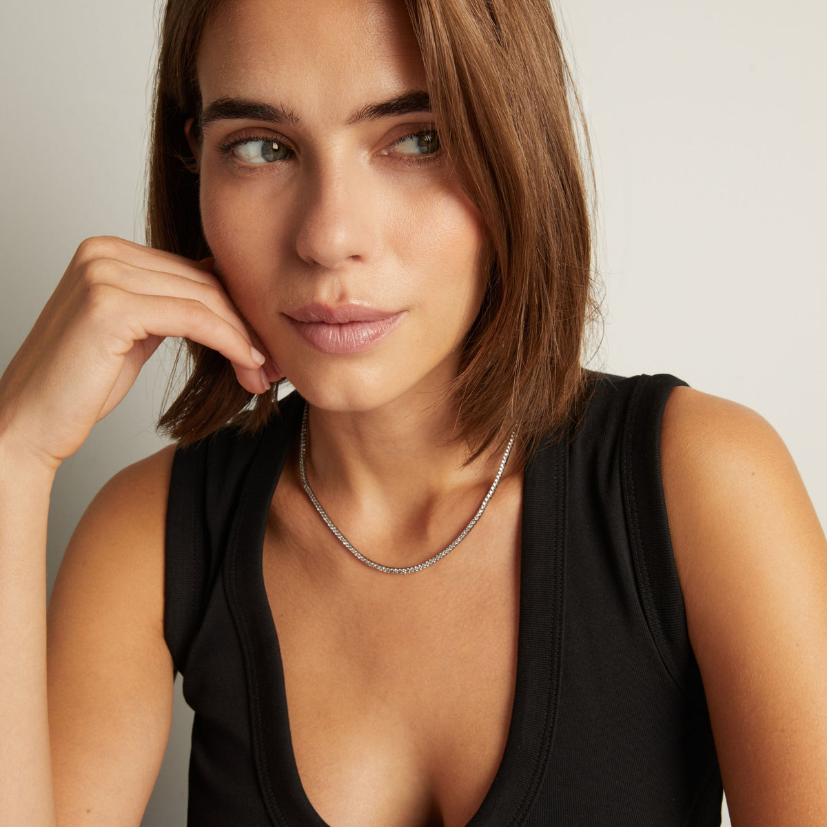 Model. Close up of woman wearing a Black Rhodium Tennis Necklace on neutral background.