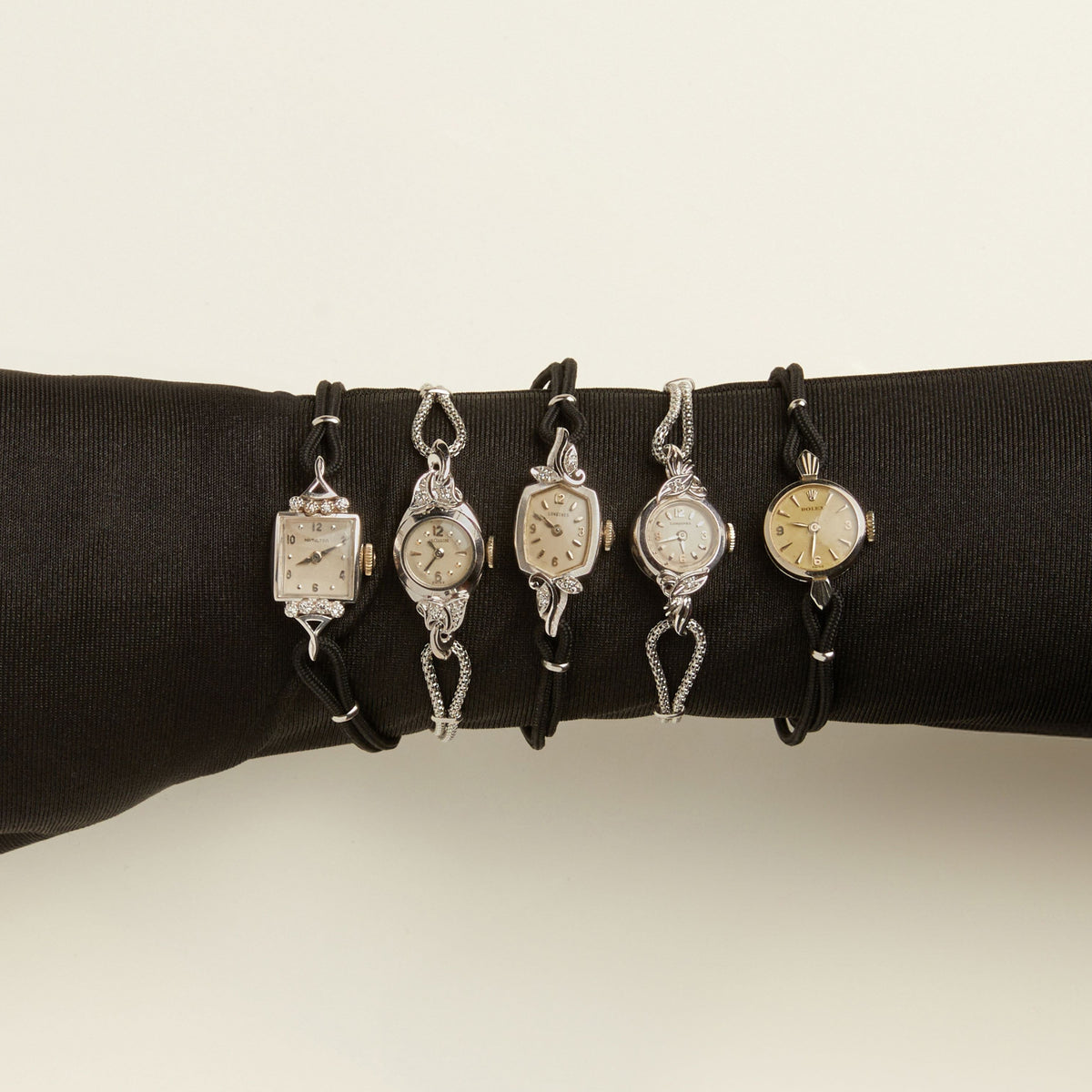 Model. Close up of 5 silver diamond watches on a neutral background