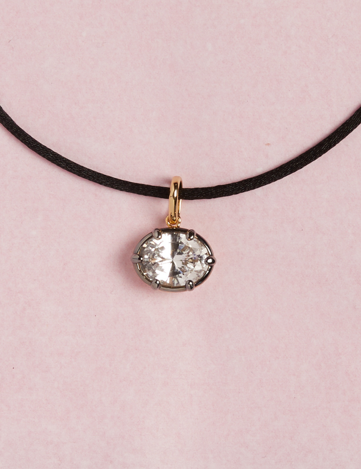 Model. Close up of cord necklace with oval gemstone pendant on pink background