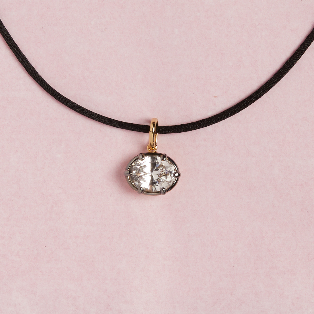 Model. Close up of cord necklace with oval gemstone pendant on pink background