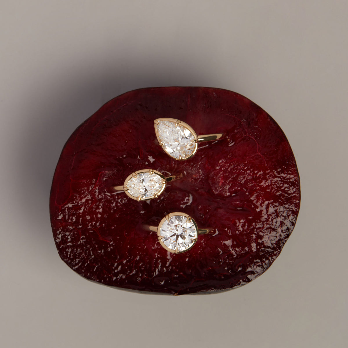 Model. 3 gold rings pressed into a plum on a neutral background.