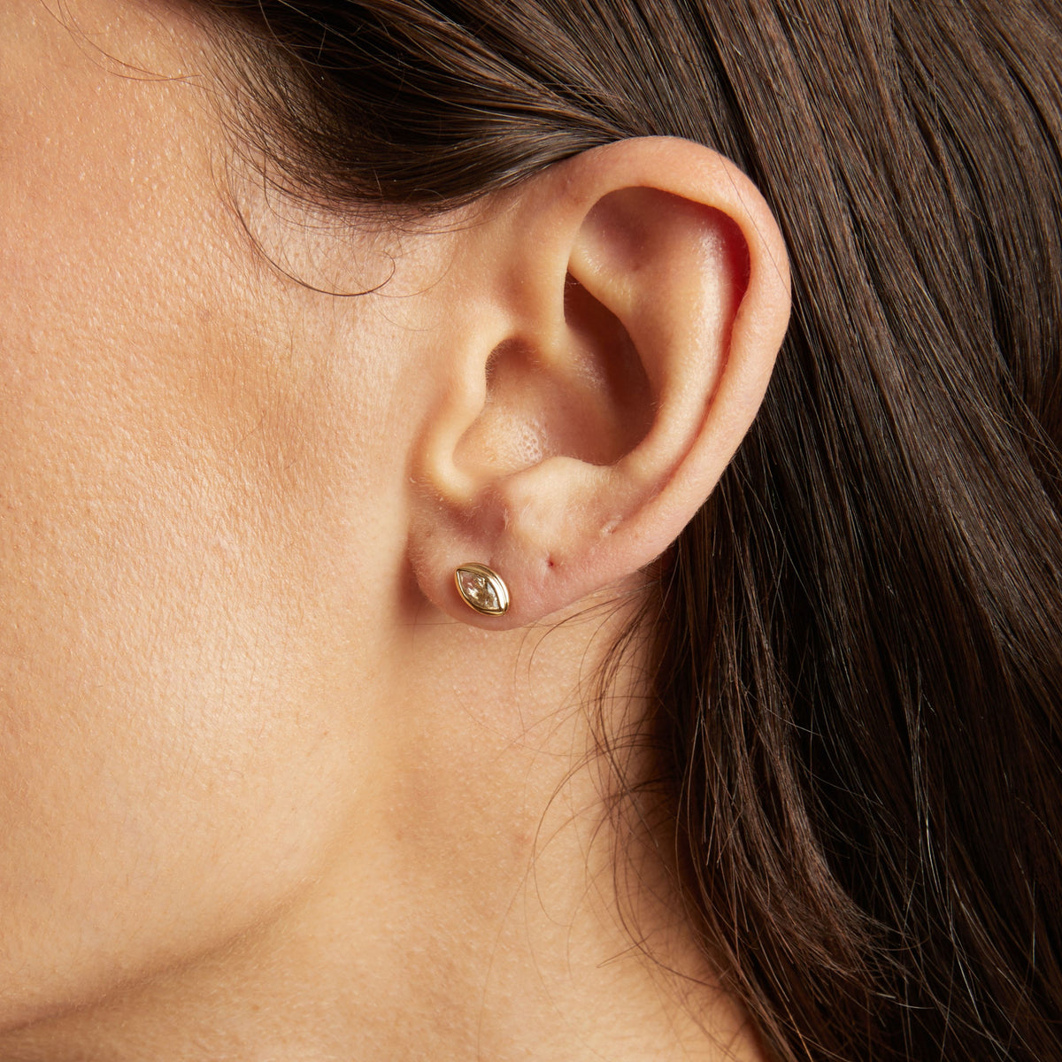 Close up of bezel stud earring on woman's ear.