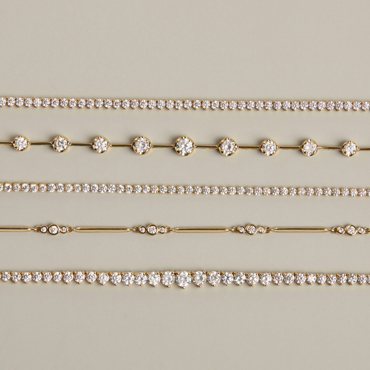 Model. Five gold and diamond bracelets of different shapes on neutral background