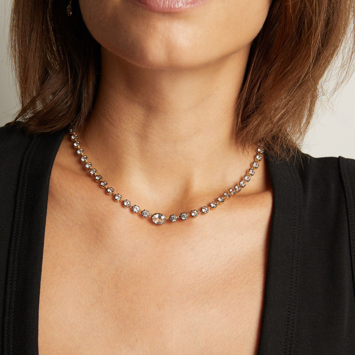 Model. Close up of a woman in a black top wearing a Georgian set tennis necklace on neutral background.