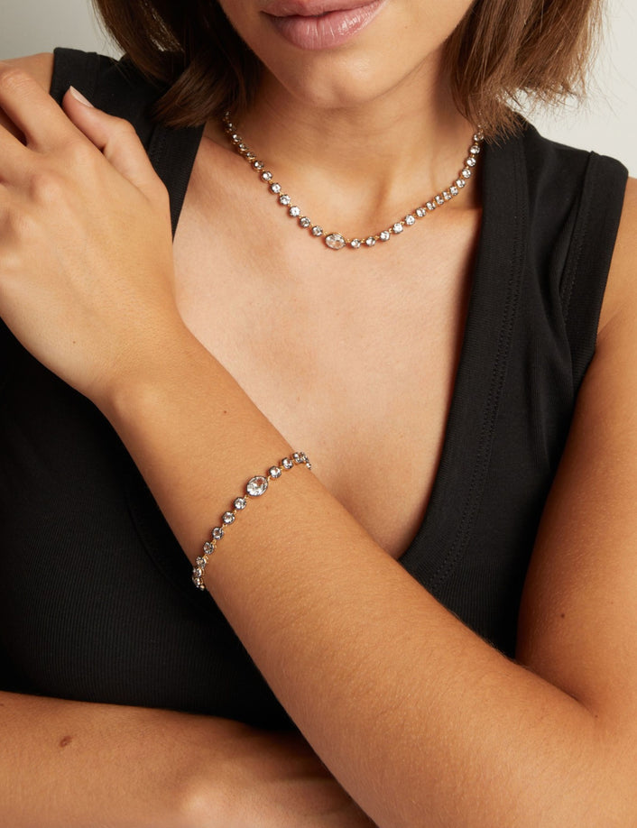Model. Close up of a woman in a black top wearing a Georgian set tennis bracelet and necklace on neutral background.