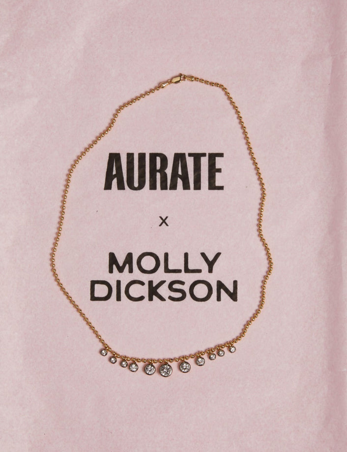 Model. Close up of gemstone chain necklace on pink background.