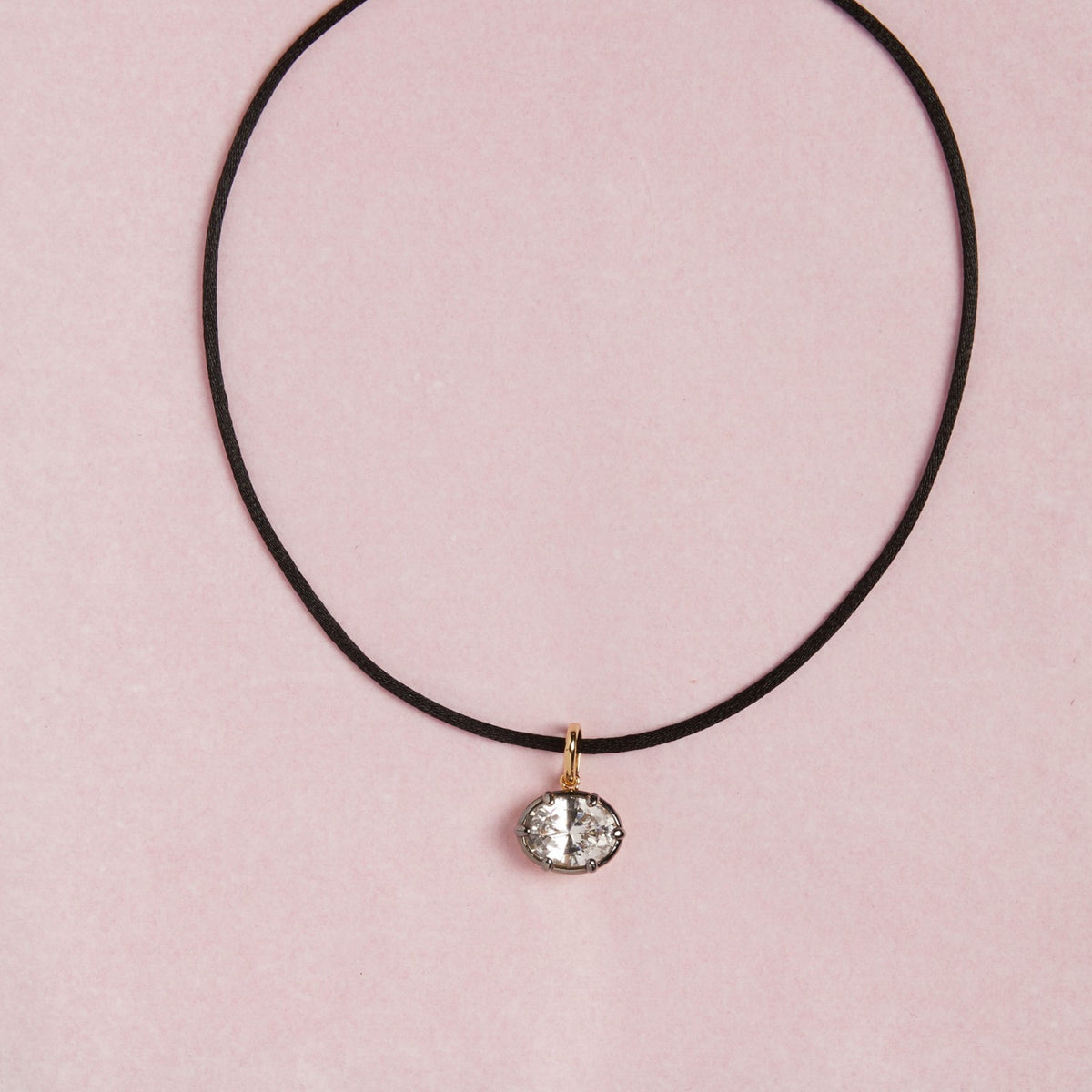 Model. Close up of cord necklace with oval gemstone pendant on pink background