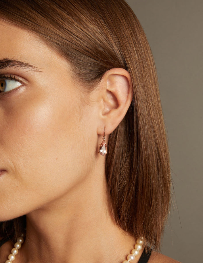 Model. Close up of a woman wearing a morganite gemstone drop earring on neutral background.