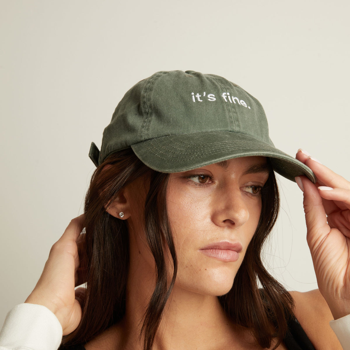 Woman wearing a green cap with 'it's fine' text on a plain background