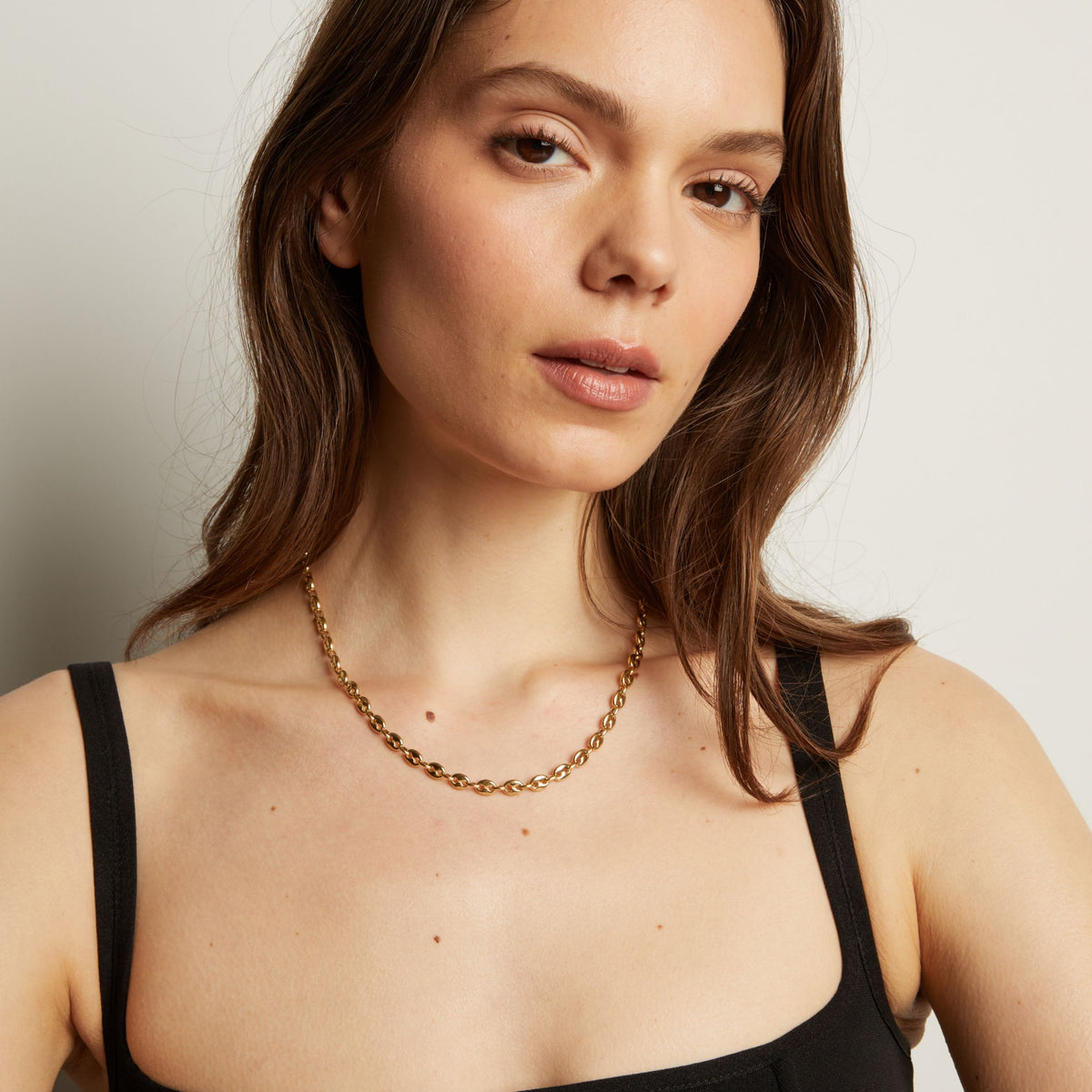 Gold chain necklace on woman in black tank top. 