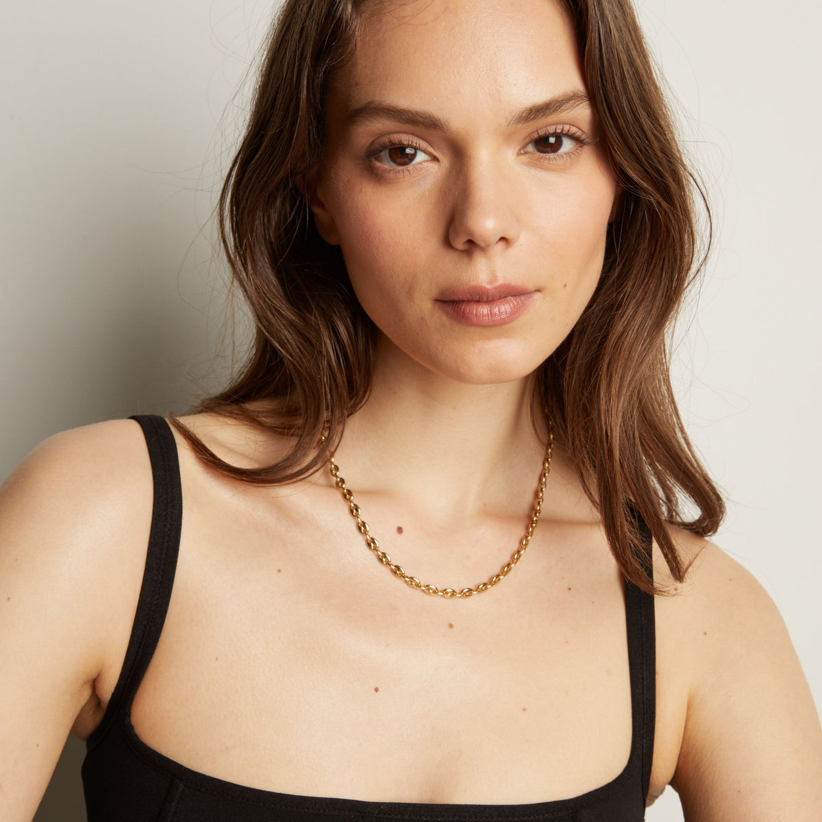 Gold chain necklace on woman in black tank top.