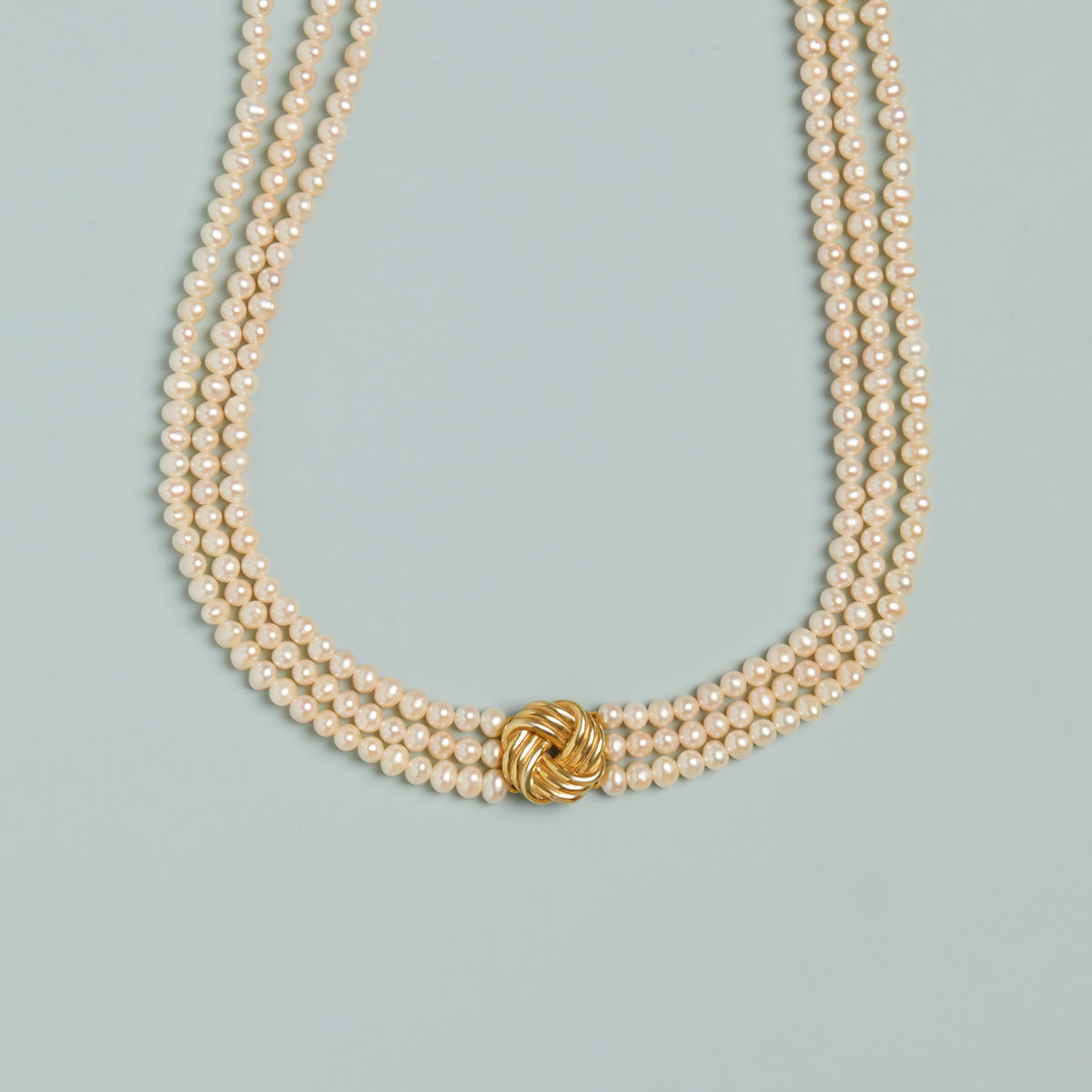 Model. Pearl necklace with a gold clasp on a light blue background