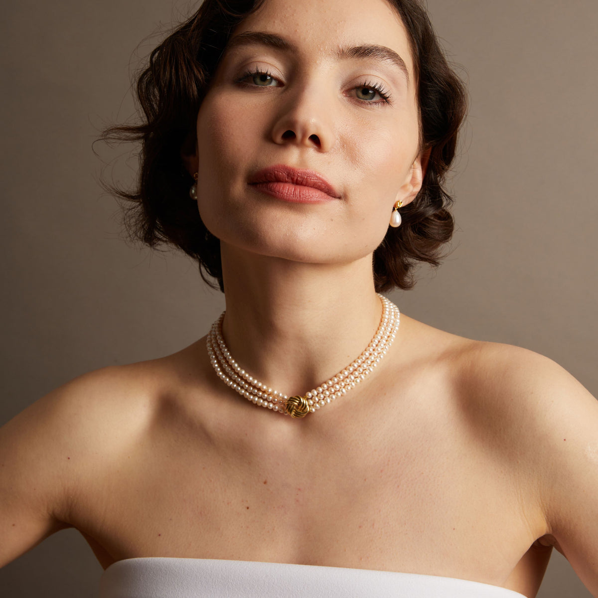 Pearl necklace on woman with neutral background. 