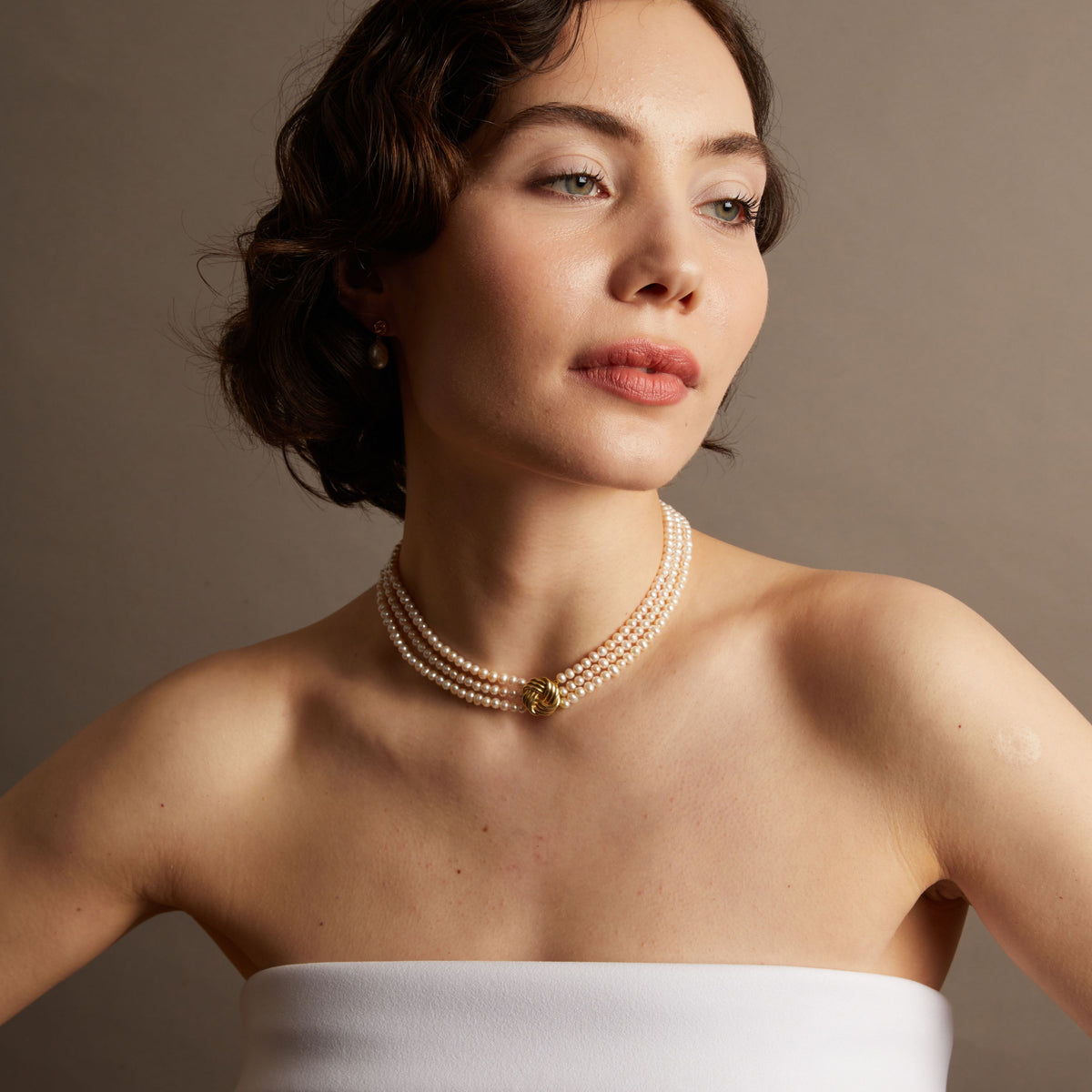 Pearl necklace on woman with neutral background. 