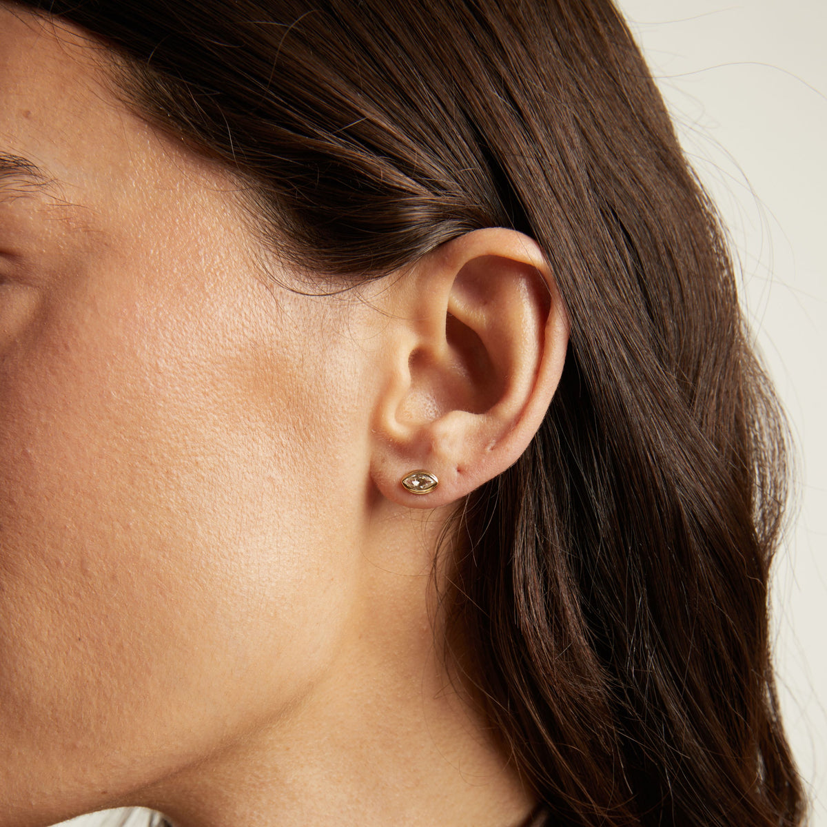 Model. Close up of bezel stud earring on woman's ear.