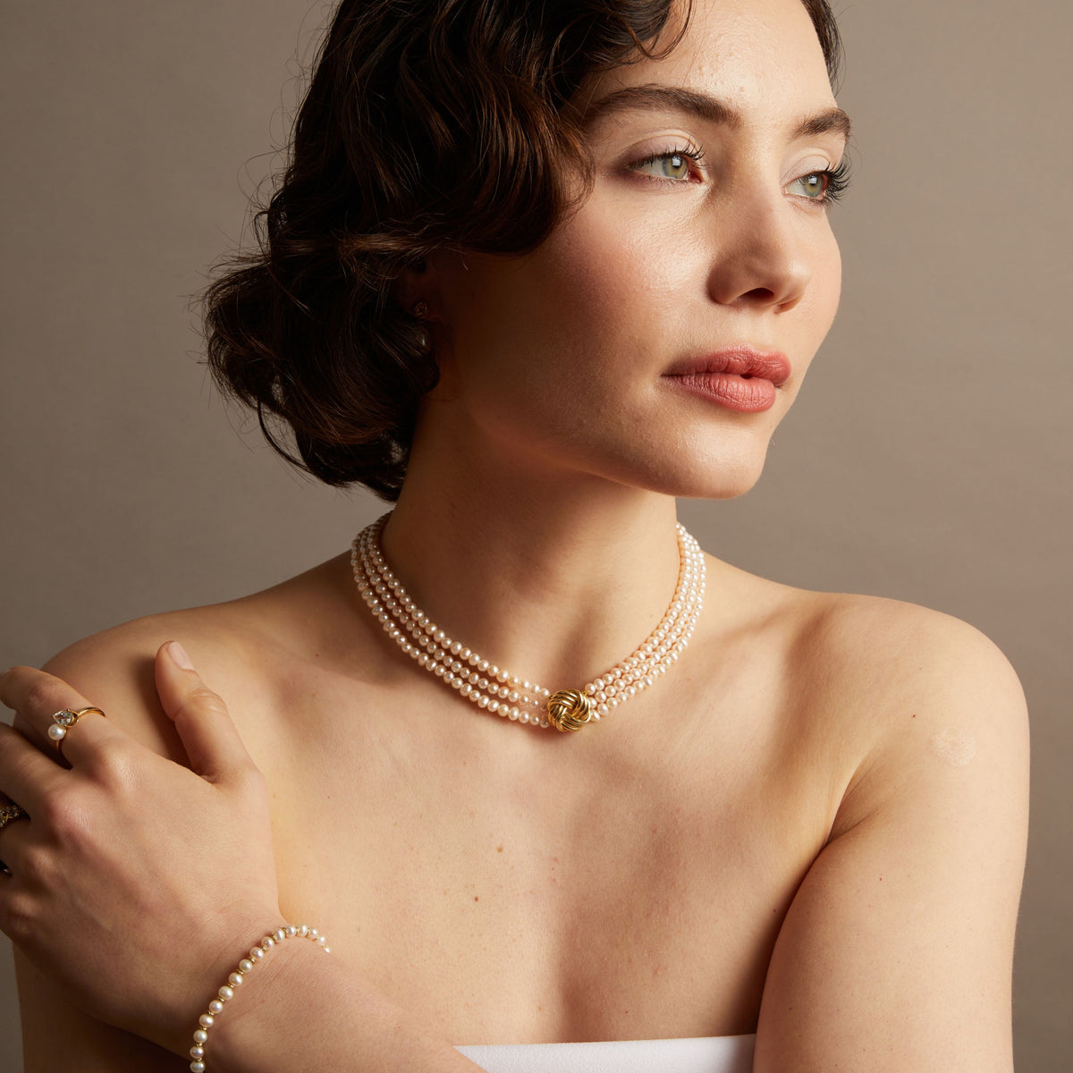 Pearl necklace on woman with neutral background. 