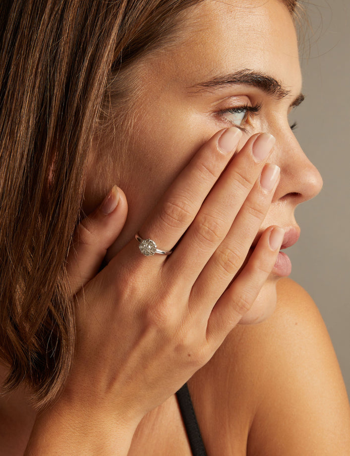 Model. Close up of a woman wearing a diamond flower ring on neutral background.