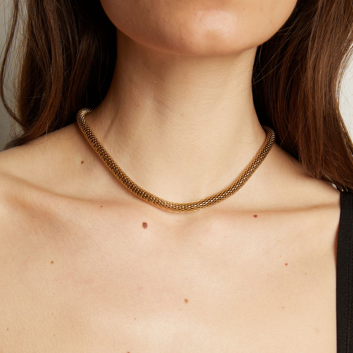 Gold chain necklace on woman in black tank top.