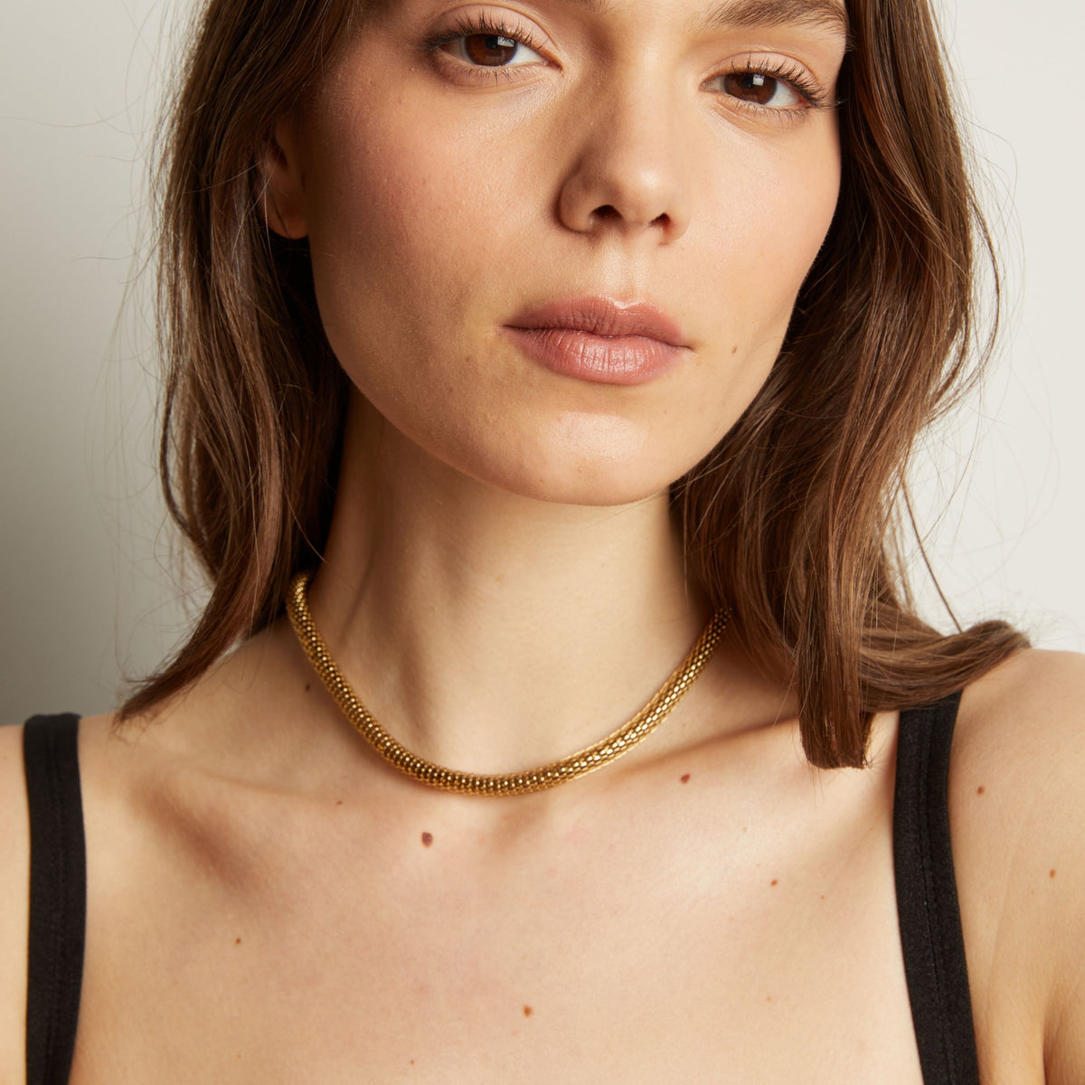 Gold chain necklace on woman in black tank top.