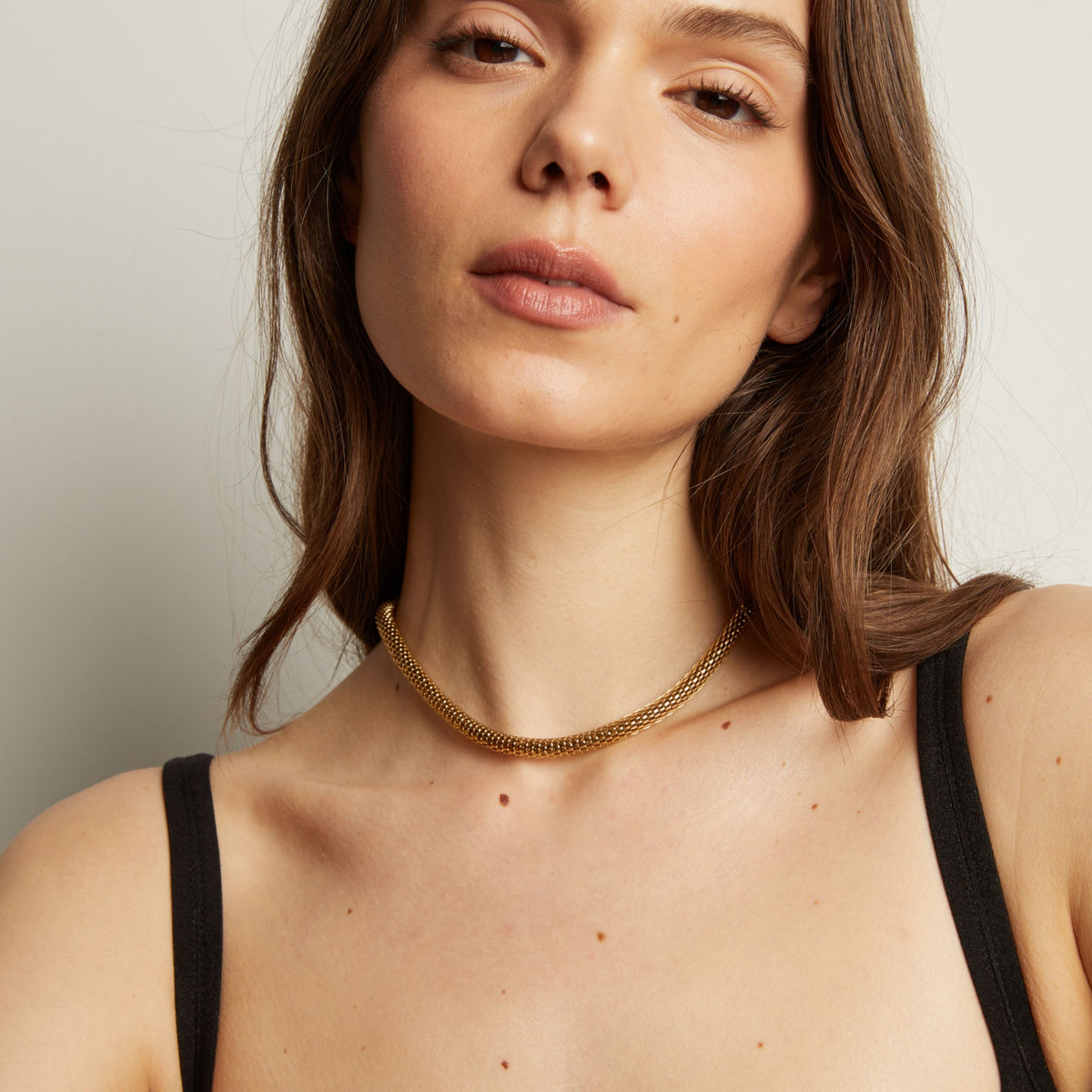 Gold chain necklace on woman in black tank top.