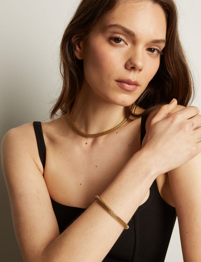 Gold chain bracelet and necklace on woman in black tank top. Model