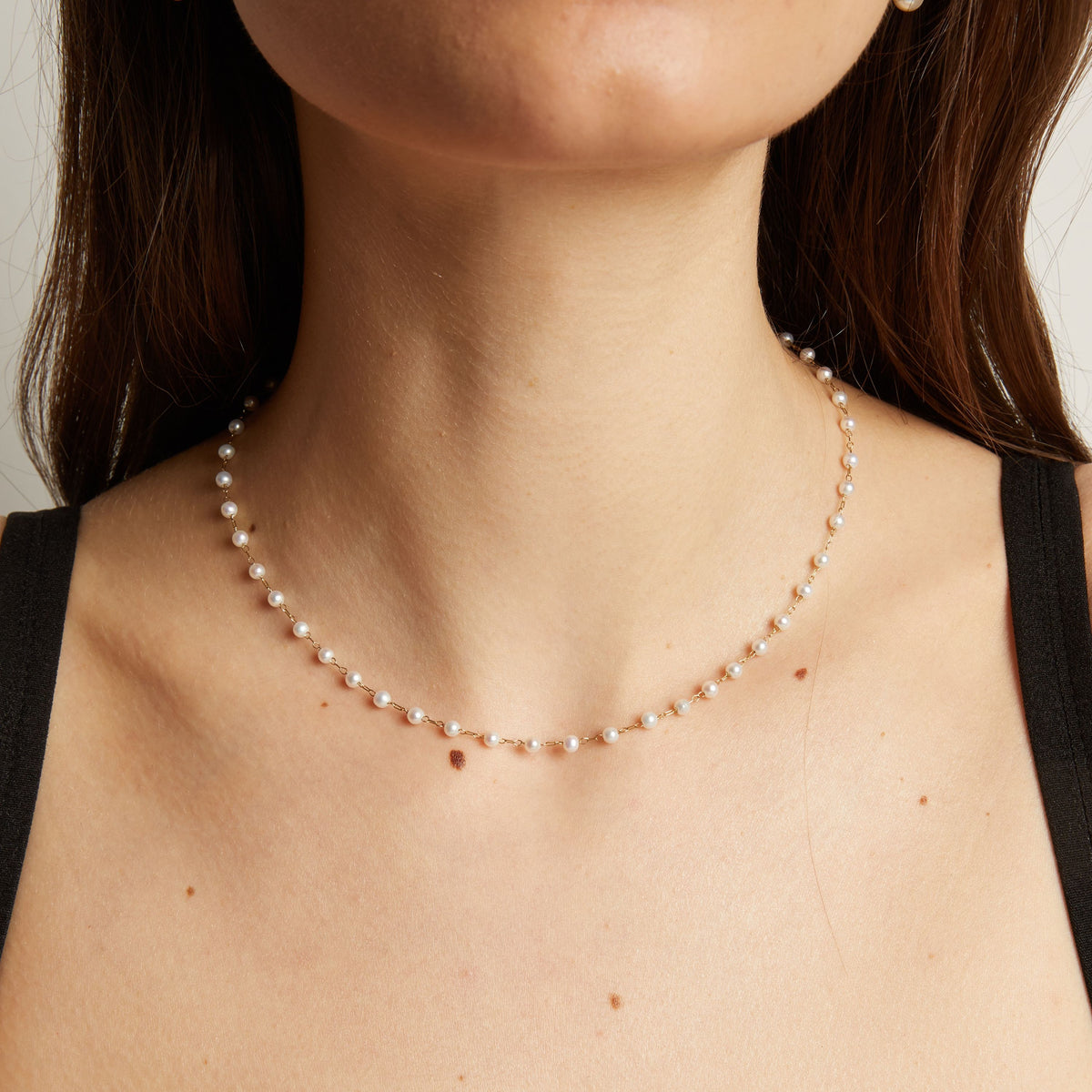 Pearl necklace worn by a person with a neutral background.