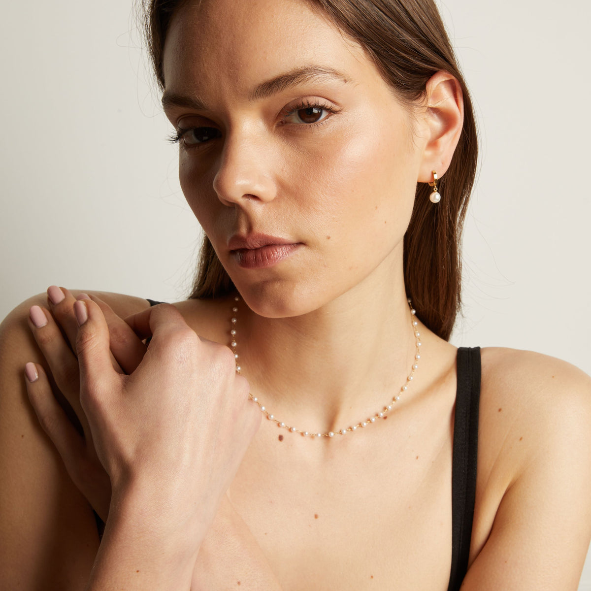 Pearl necklace worn by a person with a neutral background.