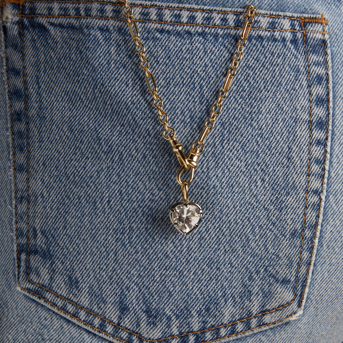 Model. Close up of a Heart Georgian Pendant on a chain resting on denim. 