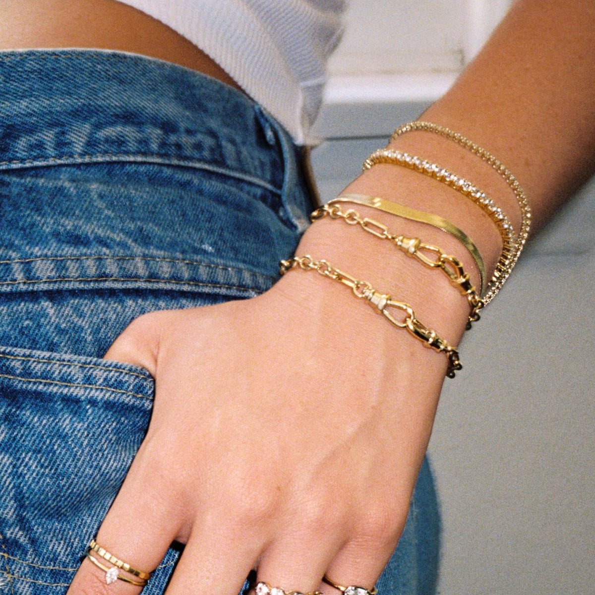 Model. Close up of woman's wrist with stacked gold bracelets. 