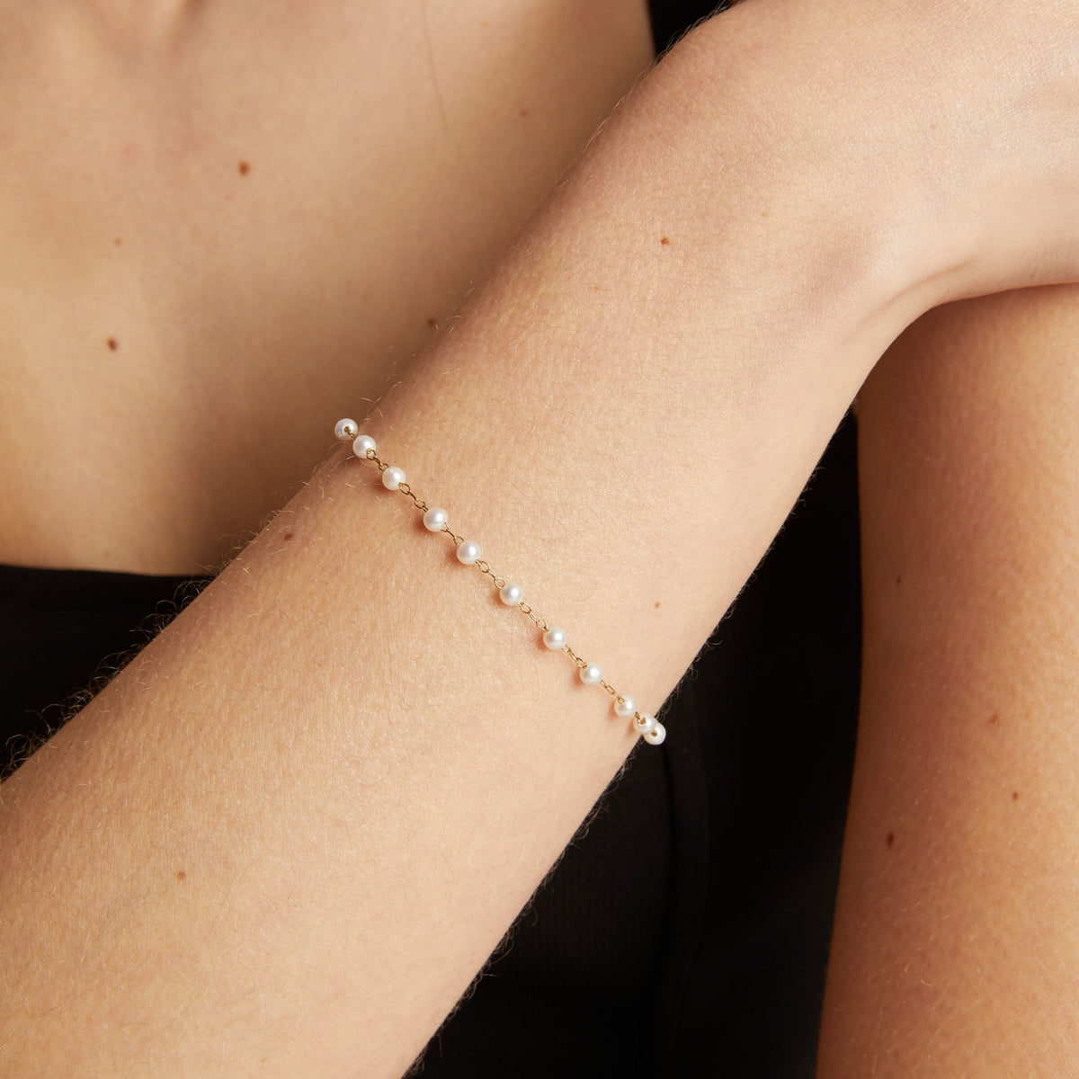 Model. Close up of a pearl bracelet on woman with neutral background.