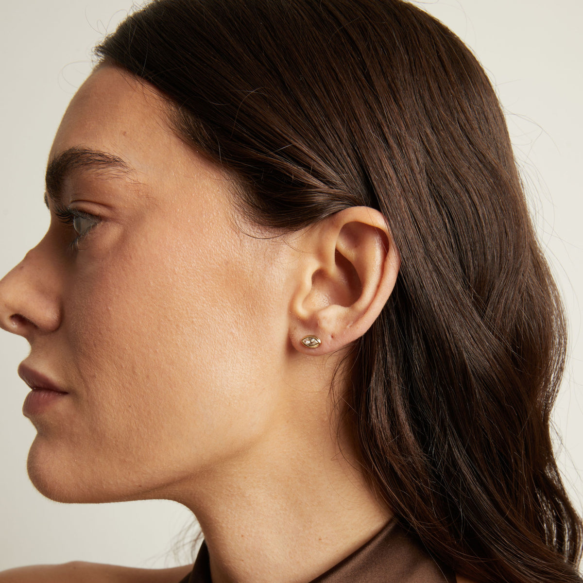 Close up of a woman wearing a bezel stud earring.