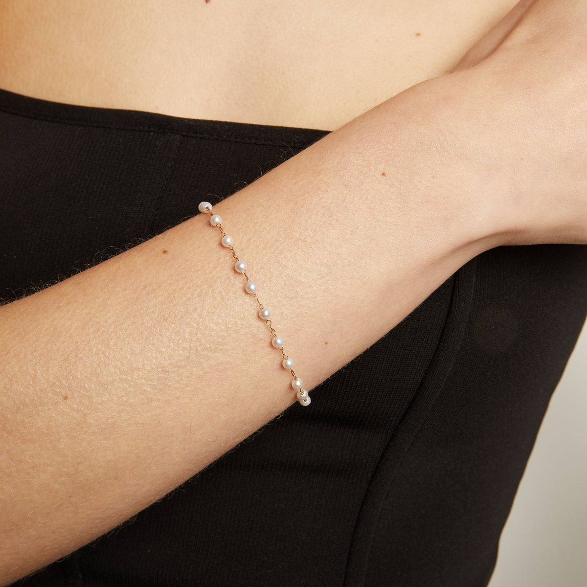 Close up of a pearl bracelet on woman with neutral background.