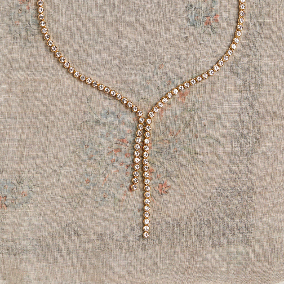 Gold diamond tennis necklace on pattern background.