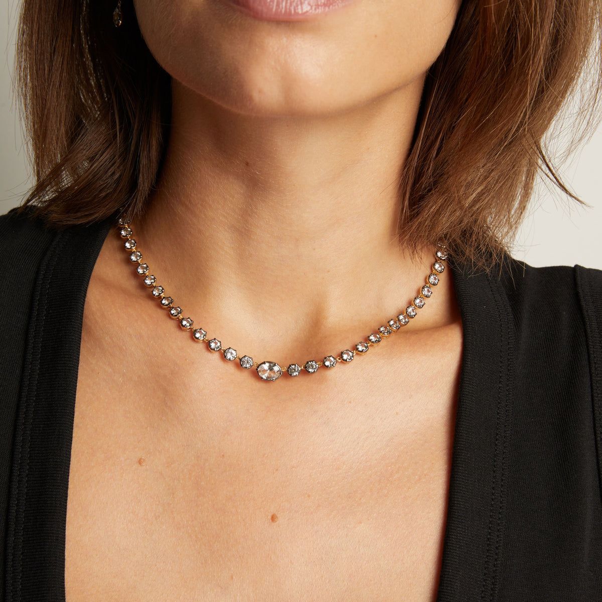 Model. Close up of a woman in a black top wearing a Georgian set tennis necklace on neutral background.