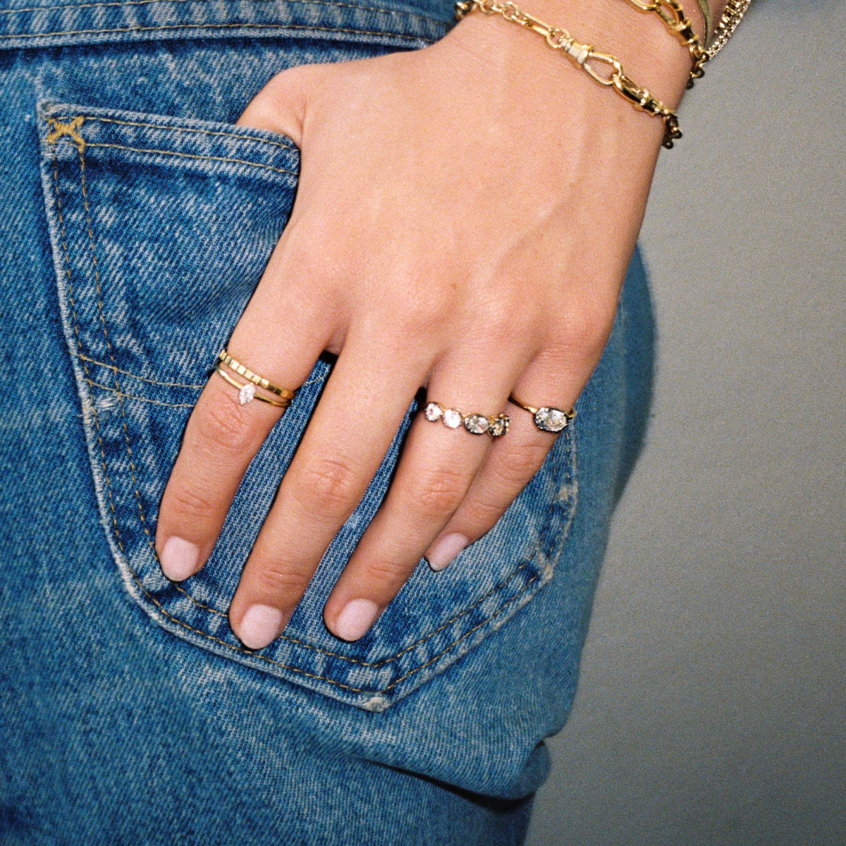 Model. Close up of a woman's hand on her jeans with various rings. 