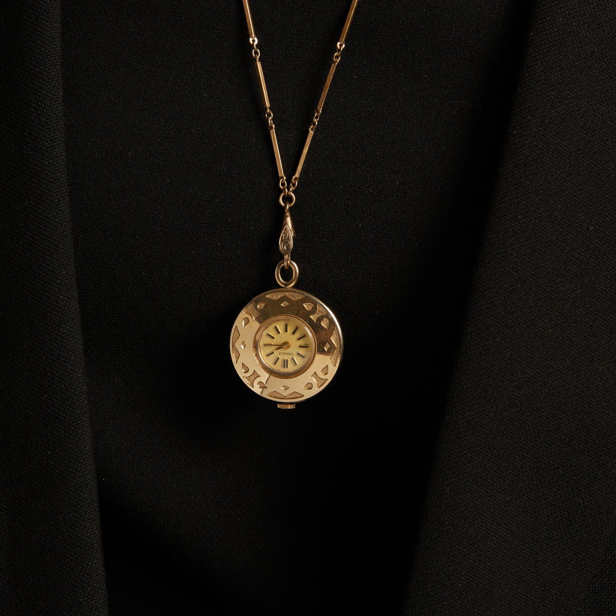 Model. Close up of a woman wearing a large watch pendant necklace on neutral background.