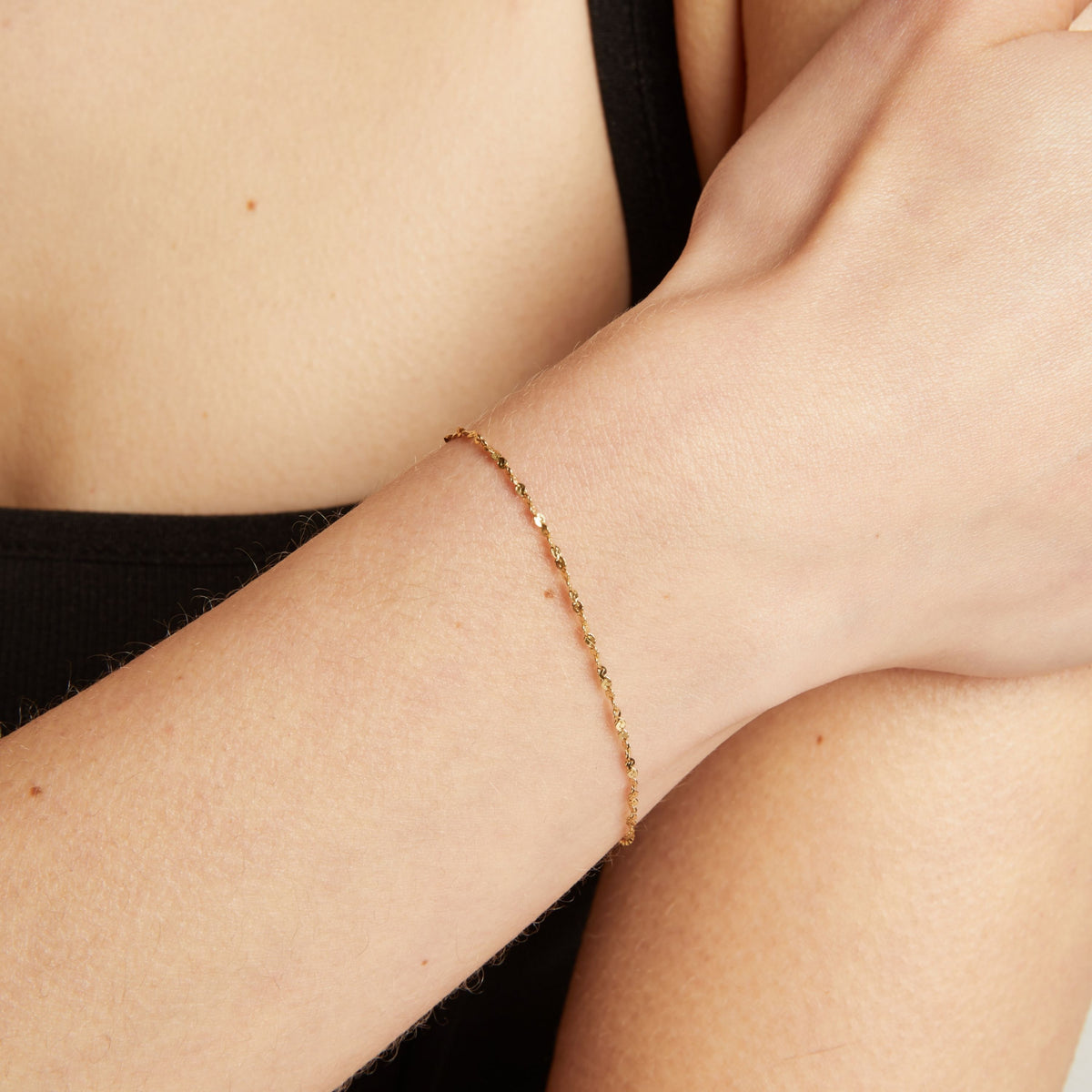 Gold bracelet on a person's wrist against a neutral background.