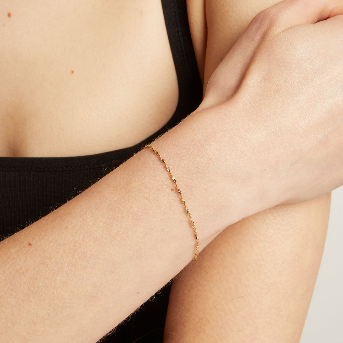 Gold bracelet on a person's wrist against a neutral background.