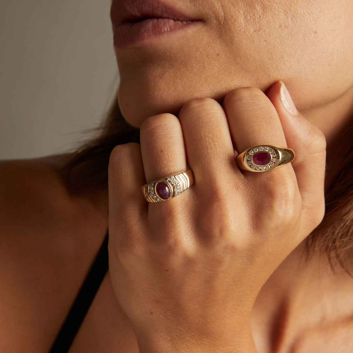 Model. Close up of woman wearing red ruby statement rings on neutral background. 