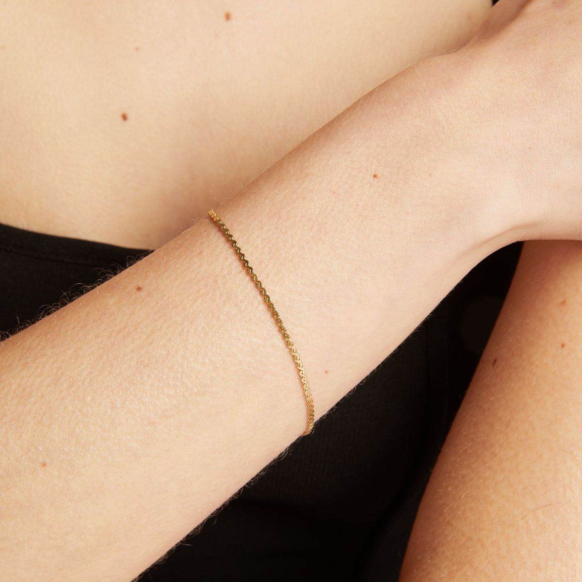 Gold bracelet on a person's wrist with a neutral background.