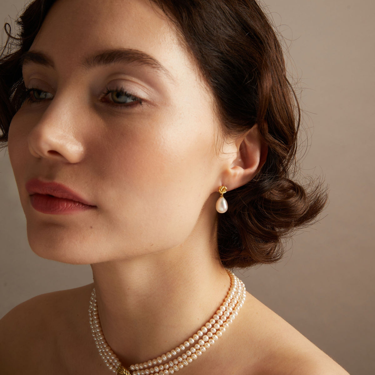 Model. Pearl knot earrings and necklace on woman with neutral background. 