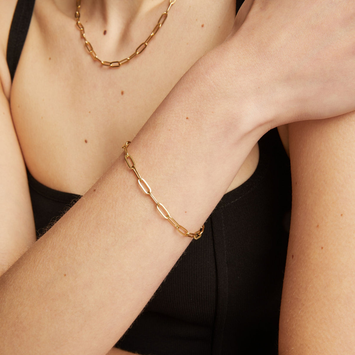 Gold chain bracelet on a person's wrist with a neutral background.