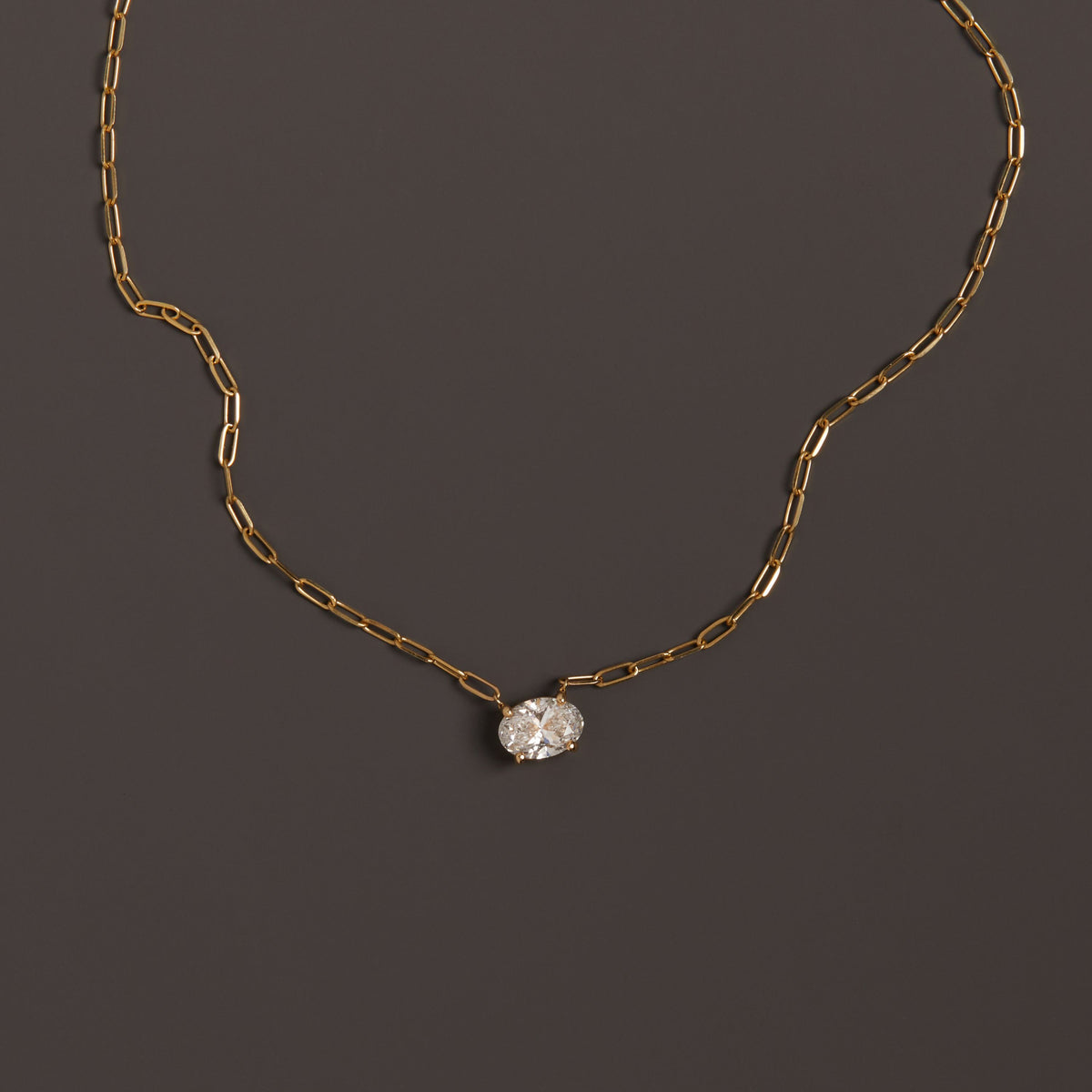 Model. Close up of diamond solitaire necklace on brown background.