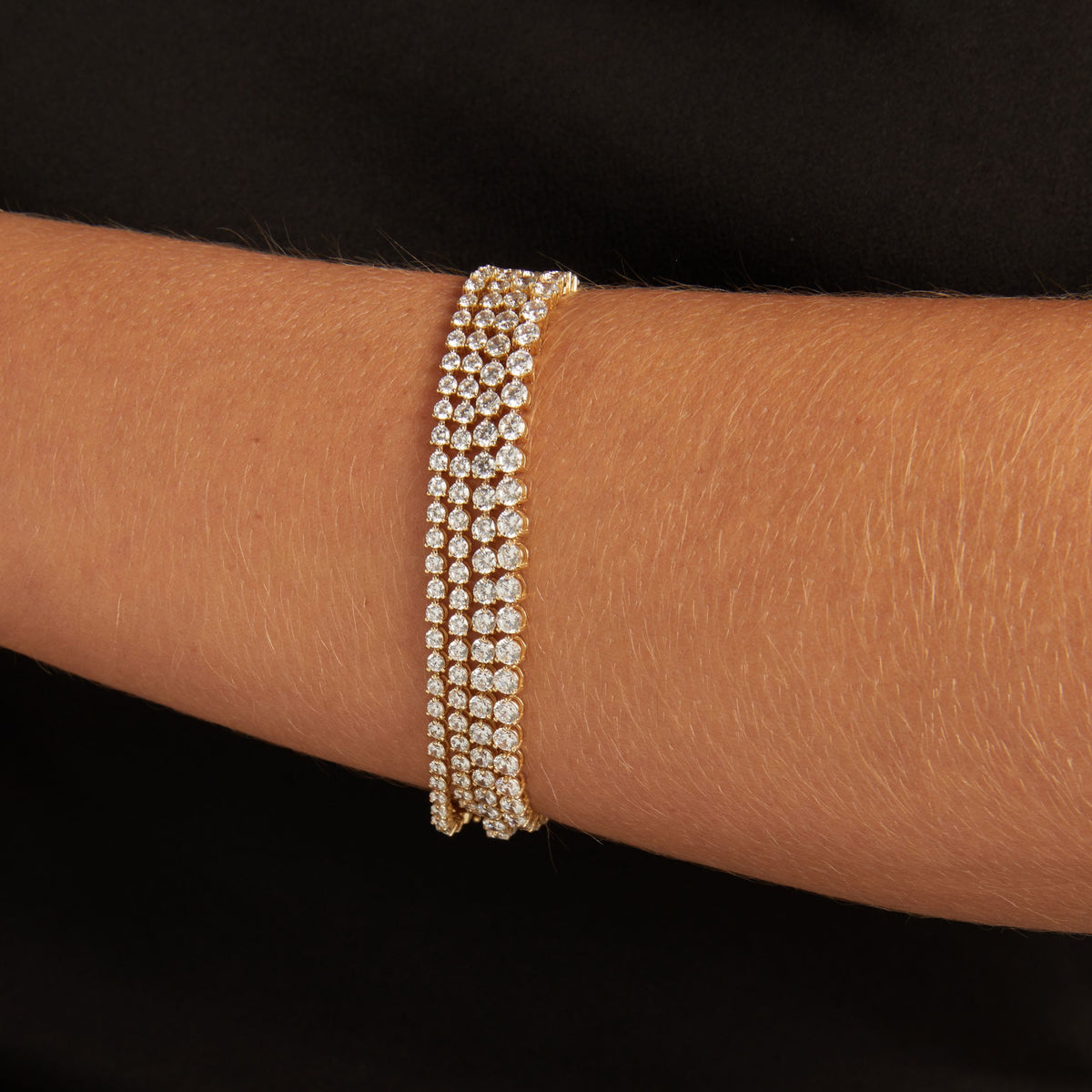 Model. Close up of a woman's wrist with four dainty diamond tennis bracelets. 