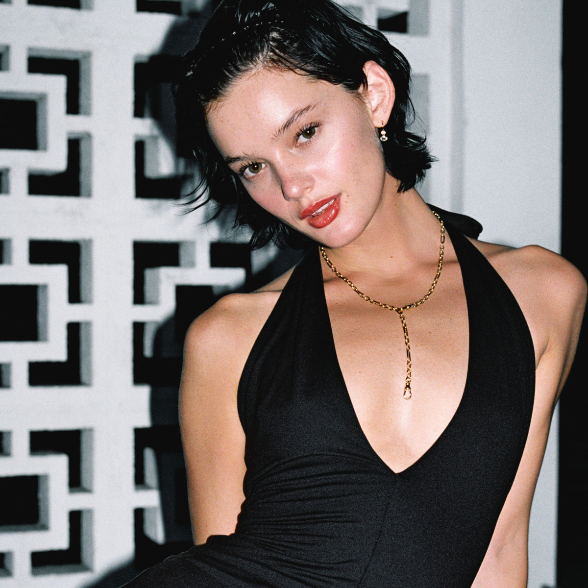 Model. Close up of woman wearing a gold chain necklace and a black dress