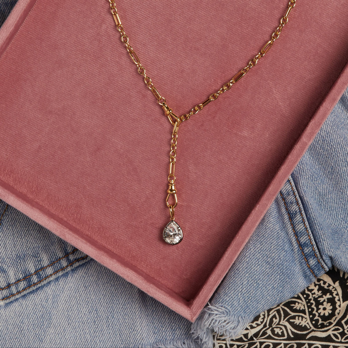 Model. Close up of gold chain necklace in pink box