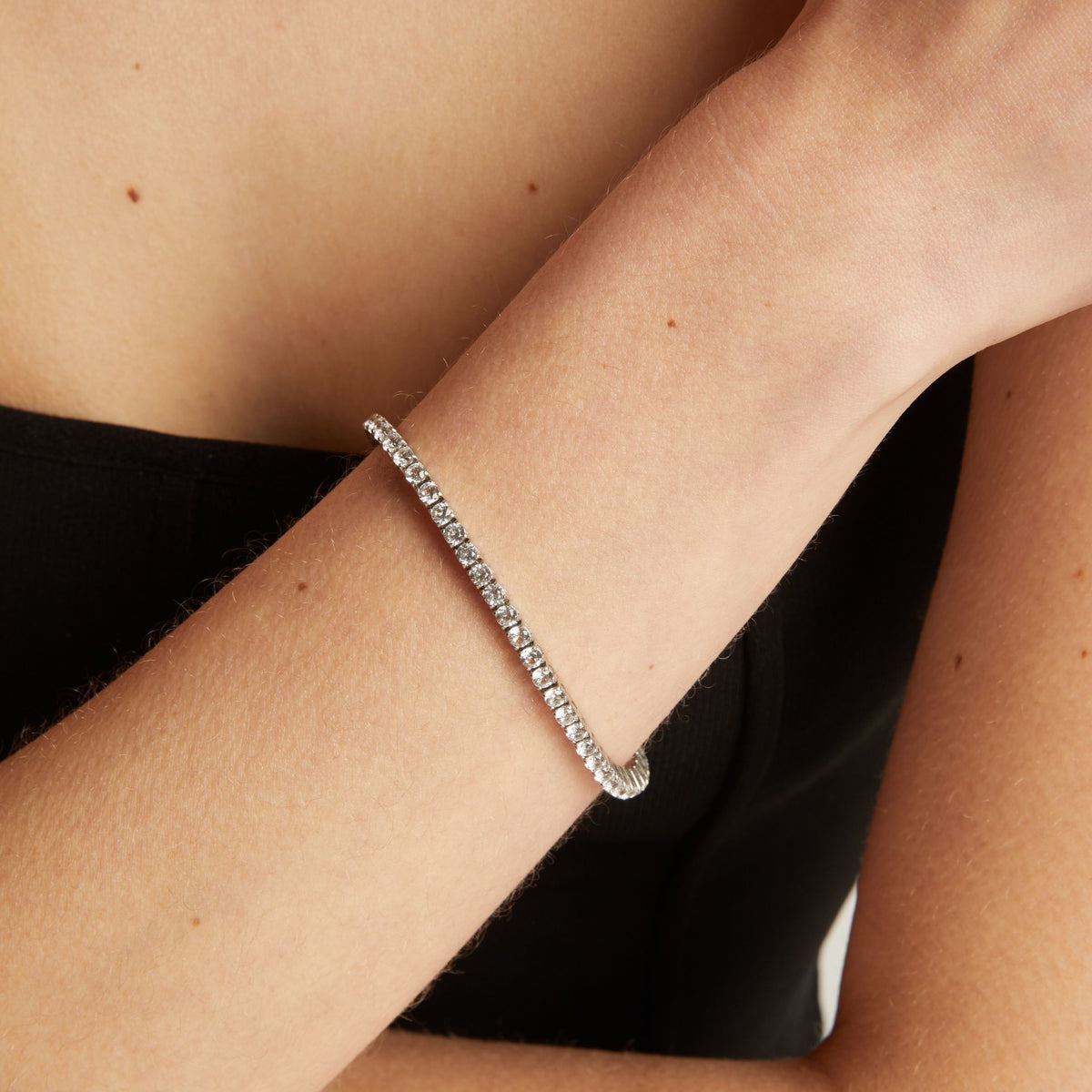 Tennis bracelet on a wrist with a black top.